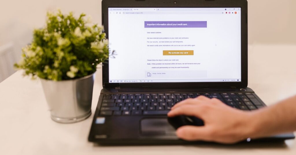 Laptop screen showing an email inbox next to a potted plant on a desk