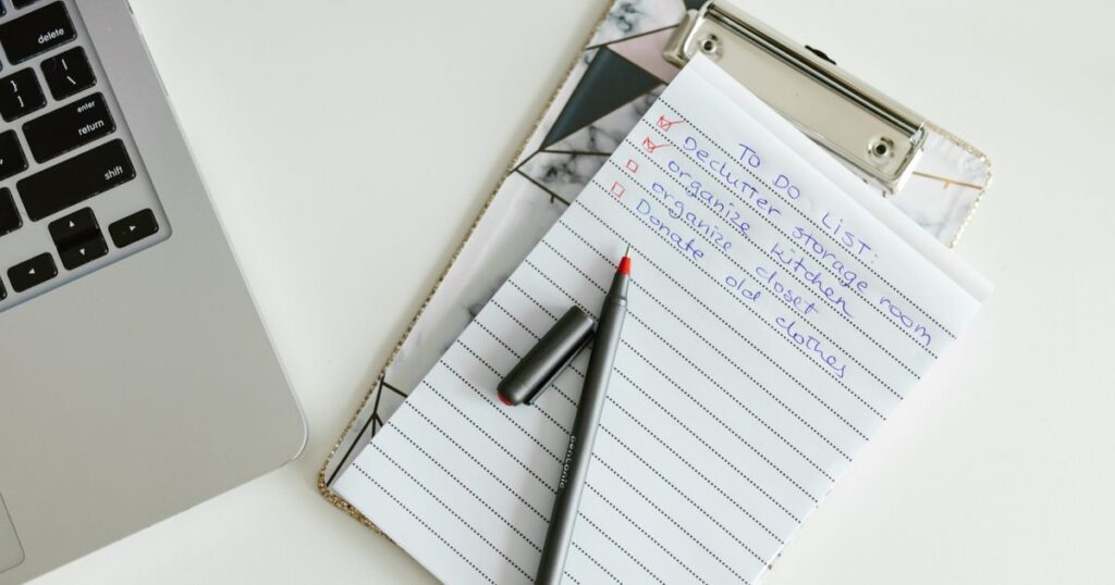 Handwritten to-do checklist on a clipboard next to a laptop